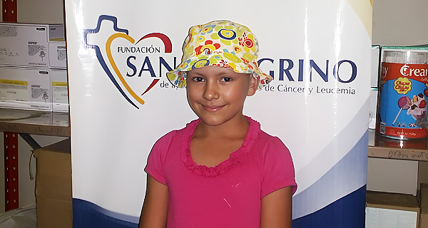 Niña sonriendo junto al banner de la Fundación San Peregrino